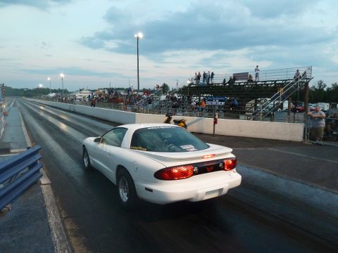 1992 Ford Mustang - A white Pontiac Firebird is on the drag strip with spectators in the stands.