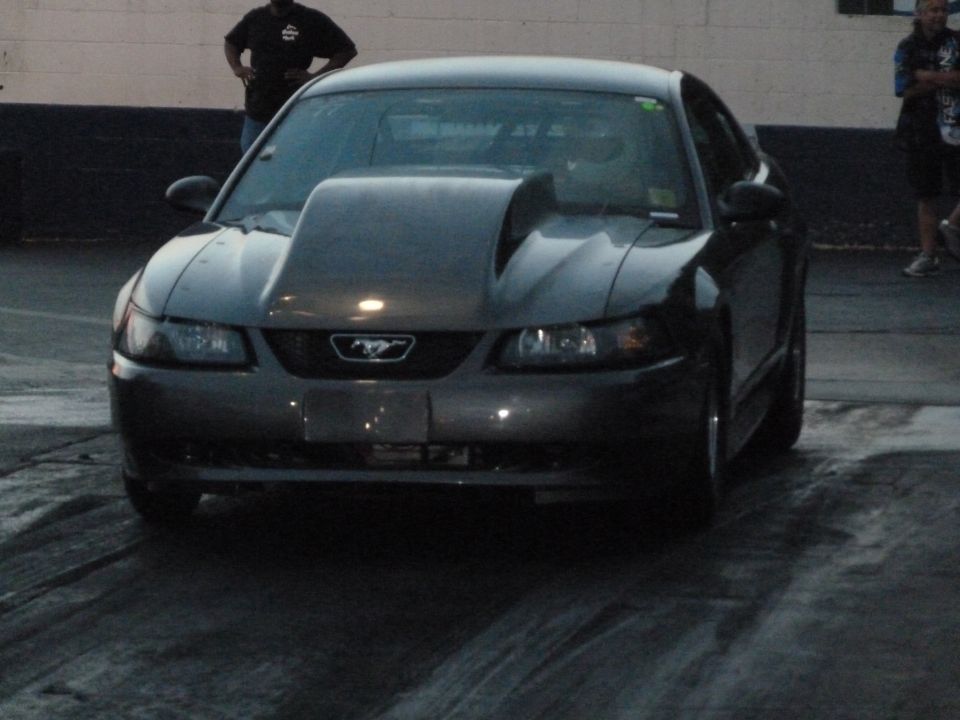 Dark gray Ford Mustang with a large hood scoop facing forward