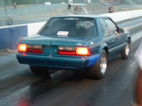 1992 Ford Mustang - A teal coupe with racing slicks and blue fender flares is captured from the rear on a drag strip.