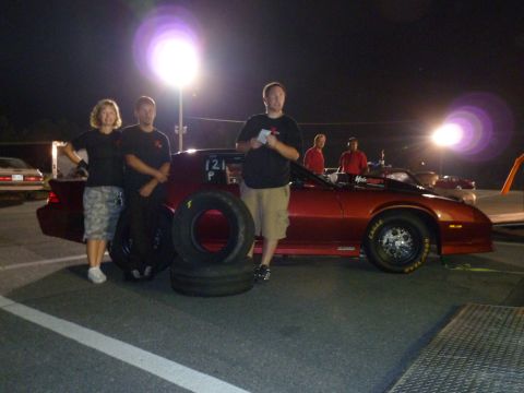 1992 Ford Mustang - A red drag car is parked on a track at night with several people standing nearby.