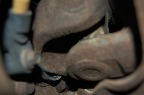 1994 Ford Bronco - A close-up, low-angle shot shows heavily rusted metal components, likely part of a vehicle's drivetrain, possibly a universal joint assembl…