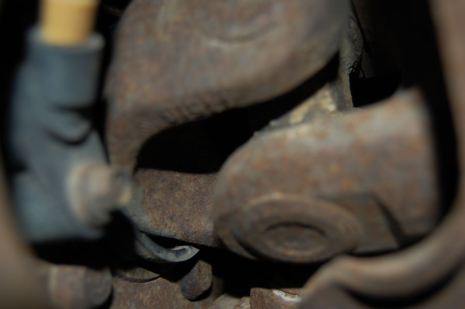 Rusted vehicle drivetrain part, possibly U-joint, with a grey electrical connector.