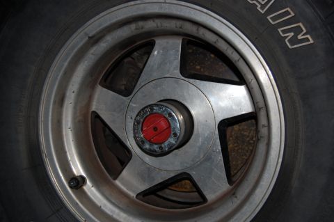1994 Ford Bronco - Close-up of a five-spoke polished aluminum wheel on an all-terrain tire, centered on a manual locking hub with a red dial marked LOCK/FREE.…