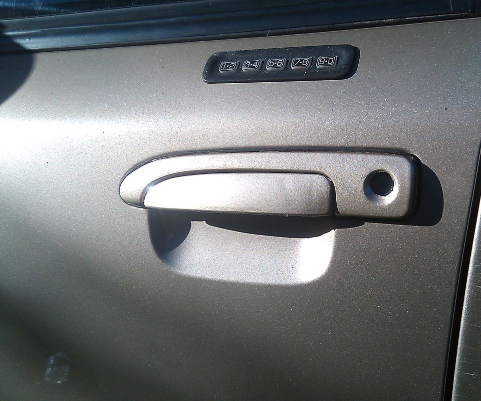 Car door with keypad entry and handle. Keypad has numbers 1-0