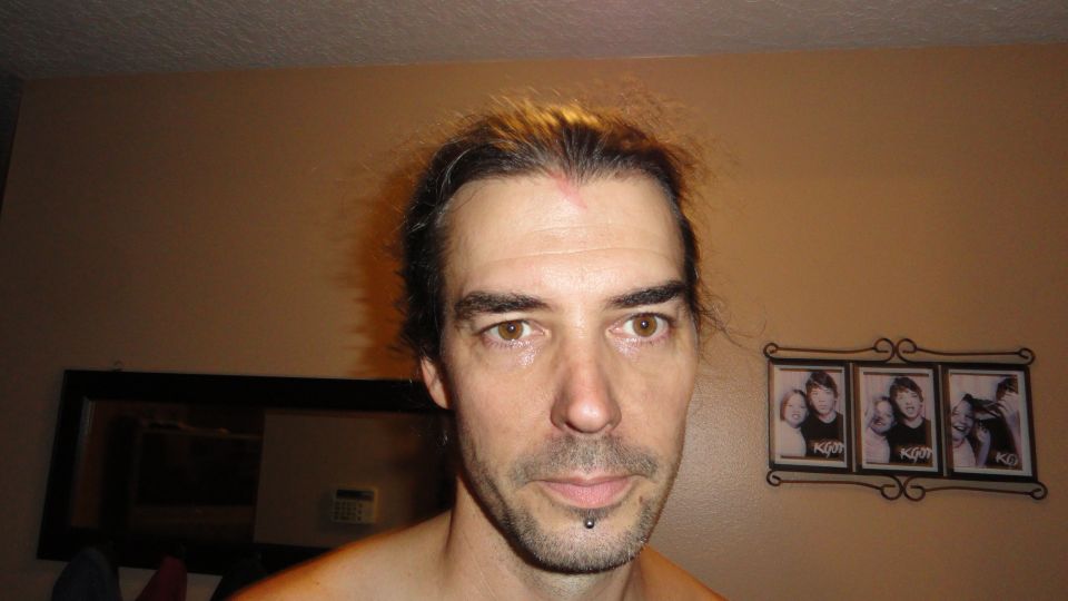 Portrait of a person indoors in front of a tan wall with framed photo strips