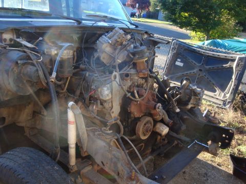 1989 Ford Bronco - Engine bay of a truck stripped down to the block, with an intake manifold, distributor, carburetor-area plumbing and exhaust manifold expos…