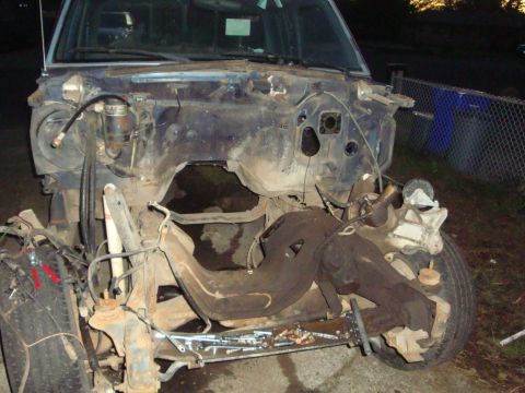 1989 Ford Bronco - The front end of a disassembled vehicle is visible, with the engine bay and suspension components exposed.