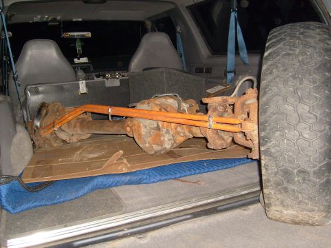 1994 Ford Bronco - Rear axle assembly being transported inside a vehicle, with a spare tire nearby.