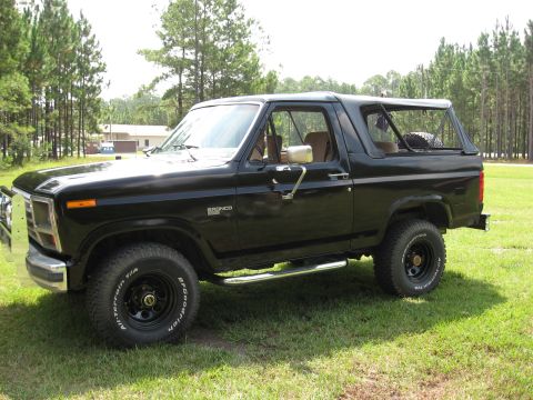 1986 Ford Bronco - This black 1986 Ford Bronco is shown from a three-quarter front view, parked on a grassy lawn.