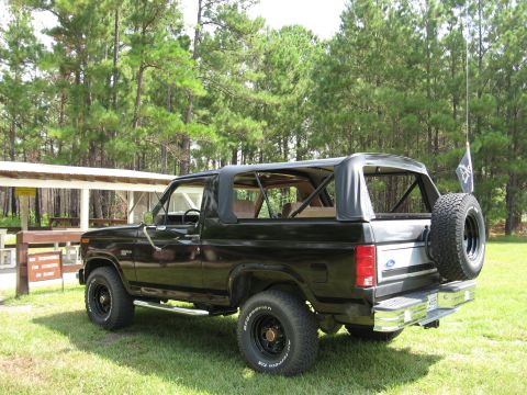 1986 Ford Bronco - Rear three-quarter view of a black 1986 Ford Bronco with its soft top removed.