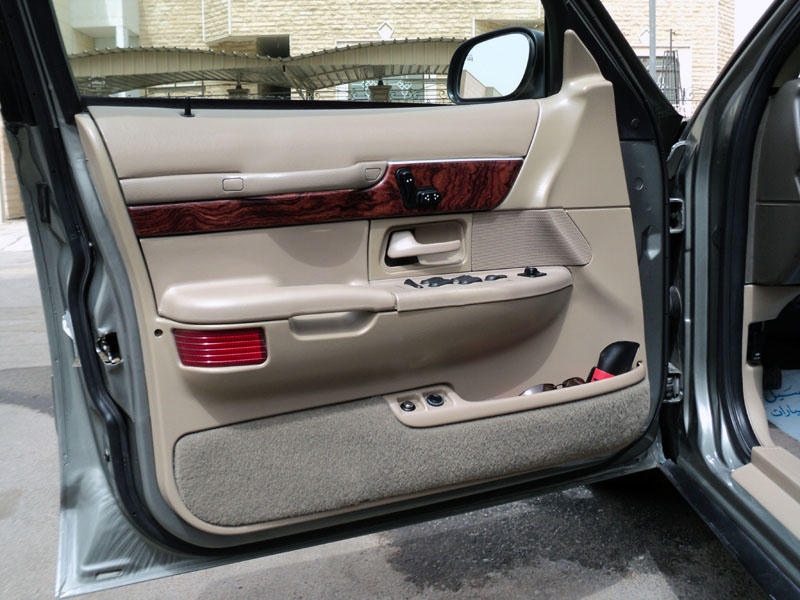 Driver's side door panel of a 2001 Mercury Grand Marquis, showing wood trim and power controls