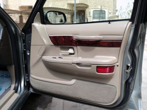 2001 Mercury Grand Marquis - Interior door panel of a 2001 Mercury Grand Marquis shows tan upholstery and wood grain trim.