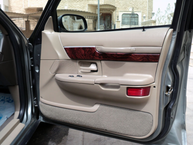 Tan interior door panel with wood trim and red reflector on a 2001 Mercury Grand Marquis