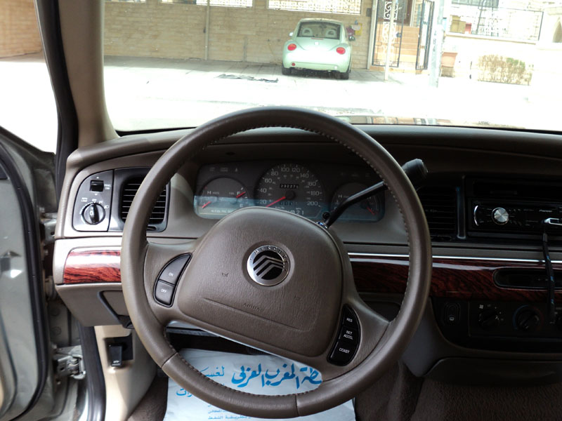 Interior of a 2001 Mercury Grand Marquis showing dashboard and steering wheel. Another car is visible through the windshield