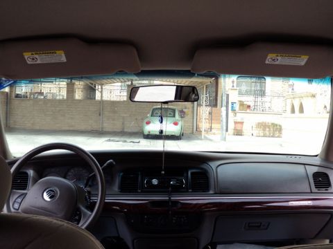 2001 Mercury Grand Marquis - The dashboard and steering wheel of a Mercury Grand Marquis are visible, with a light green Volkswagen Beetle parked outside.
