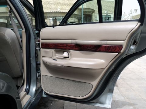 2001 Mercury Grand Marquis - Interior view of a car's door panel, showing beige upholstery and wood trim accents.