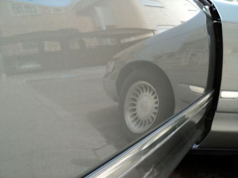 2001 Mercury Grand Marquis - The side profile of a 2001 Mercury Grand Marquis is visible, with the driver's side door ajar, revealing the interior trim and the front wh…