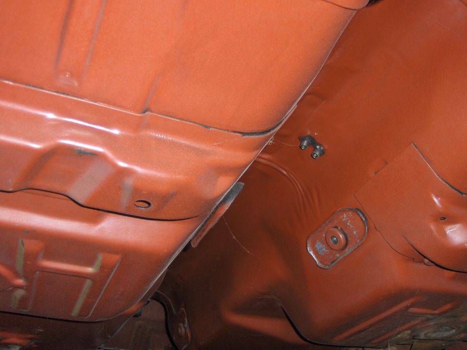 Orange painted car undercarriage with visible structural beams and mounting points