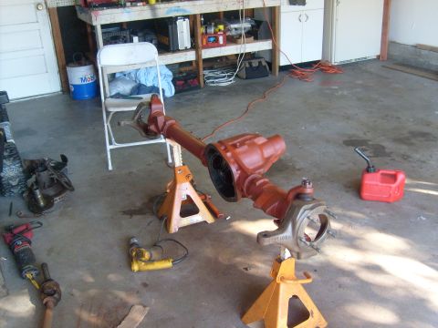 1994 Ford Bronco - A vehicle axle assembly is disassembled and supported by jack stands in a garage setting.