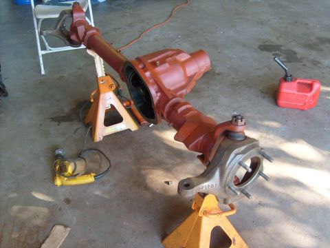 1994 Ford Bronco - A disassembled front axle assembly rests on orange jack stands in a garage setting.