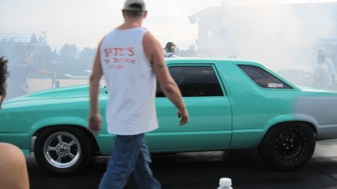 1992 Ford Mustang - A drag car is seen on the track with smoke in the background.