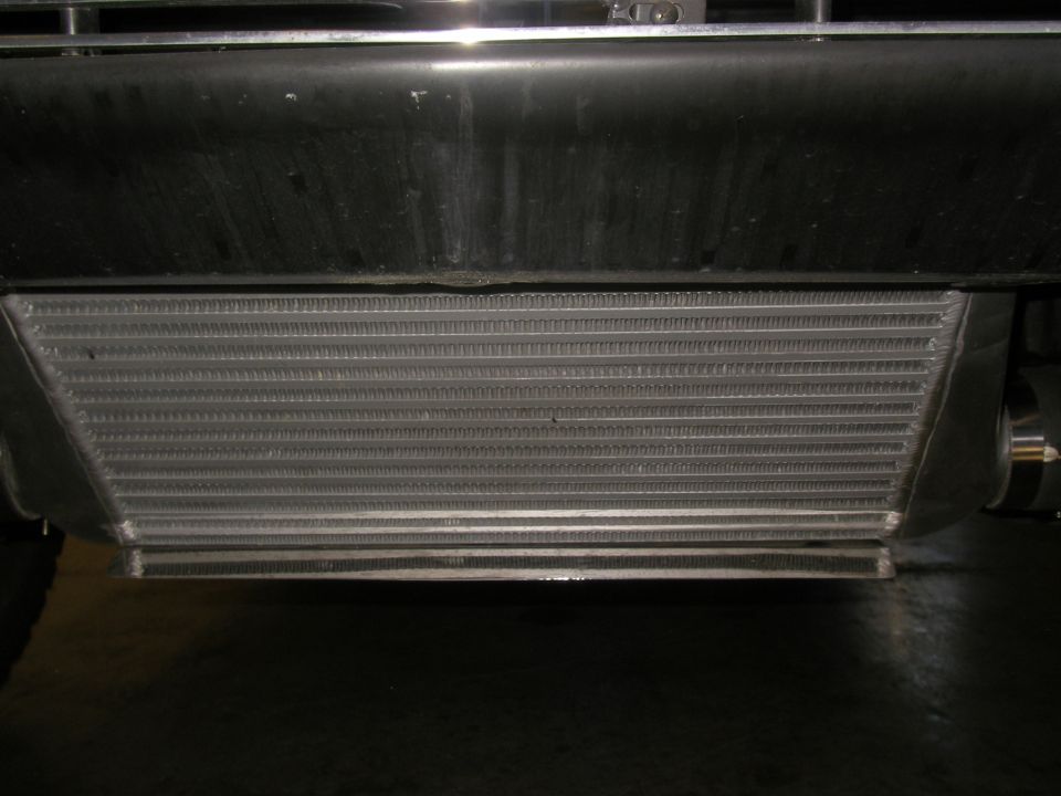 Bar-and-plate aluminum intercooler mounted below the front bumper of a truck