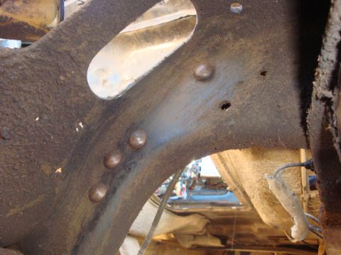 1989 Ford Bronco - Underside close-up of a rusty boxed frame rail where an old bracket has been cut off and the metal ground down to bare shiny steel, leaving…