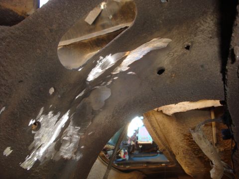 1989 Ford Bronco - Close-up view of a vehicle's corroded undercarriage frame with visible repairs and wiring.
