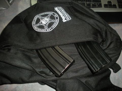 1996 Ford Bronco - A black backpack is shown with two rifle magazines protruding from an open compartment, alongside a conference logo.