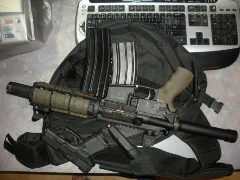 1996 Ford Bronco - An assault rifle with multiple magazines and a handgun are laid out on a black bag next to a keyboard.