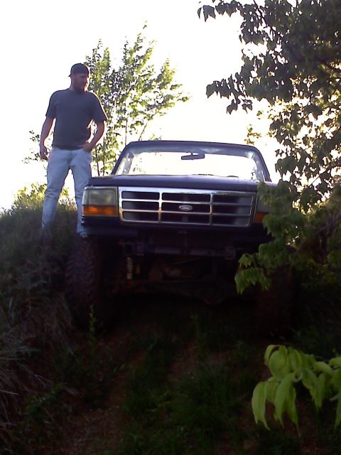 1994 Ford Bronco - A man stands next to a dark Ford truck on a grassy incline.