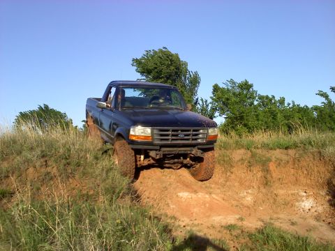 1994 Ford Bronco - This 1994 Ford Bronco navigates a steep dirt incline under a clear blue sky.