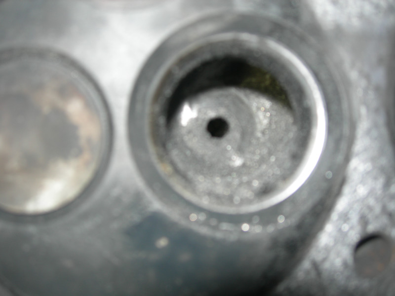 Close-up of engine cylinder head with two valve openings, one showing carbon buildup