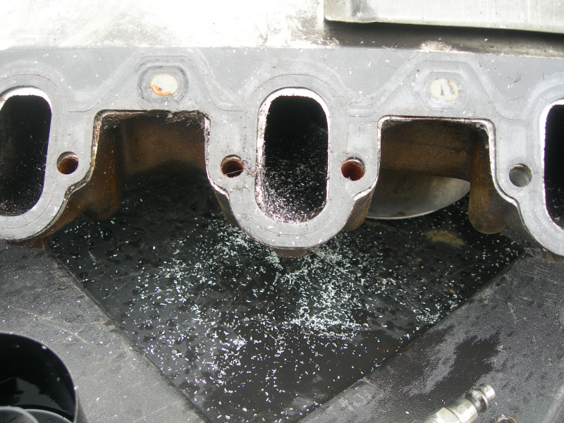Close-up of an engine intake manifold gasket surface with debris