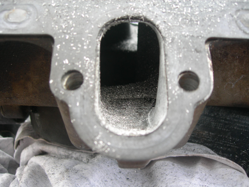 Close-up of an engine intake port with metal shavings inside. A white cloth is visible underneath
