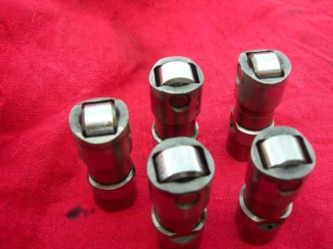 1984 Ford Bronco - Close-up of hydraulic valve lifters, likely for an engine rebuild, on a red surface.