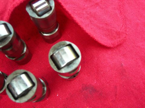 1984 Ford Bronco - Close-up of several metal engine lifters resting on a red fabric surface.