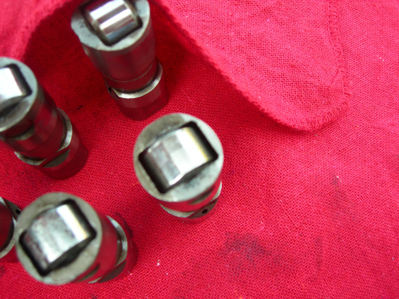 several metal engine lifters on a red cloth