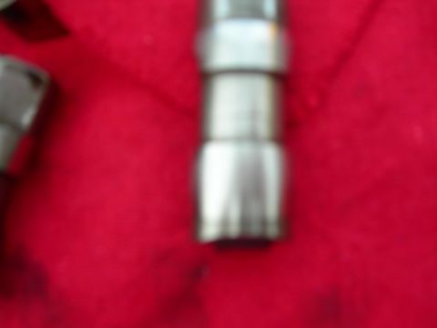 1984 Ford Bronco - A metal engine part is shown against a red background, with a website watermark visible.