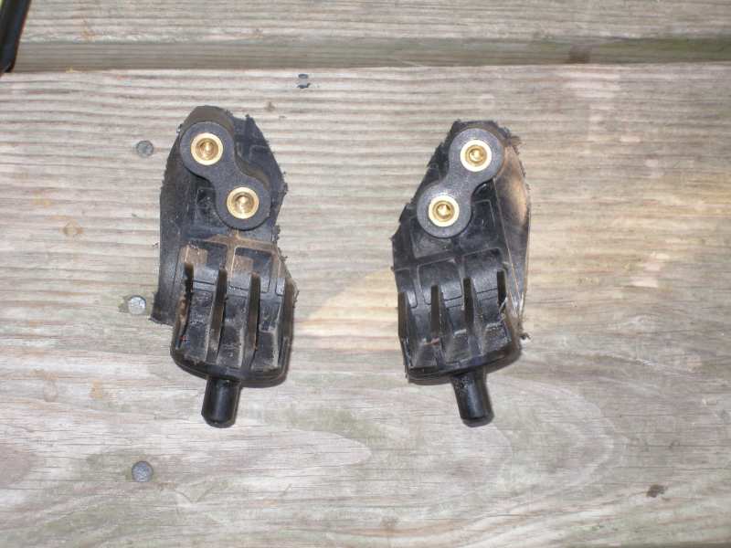 Two black rubber engine mounts with brass fittings on a wooden surface