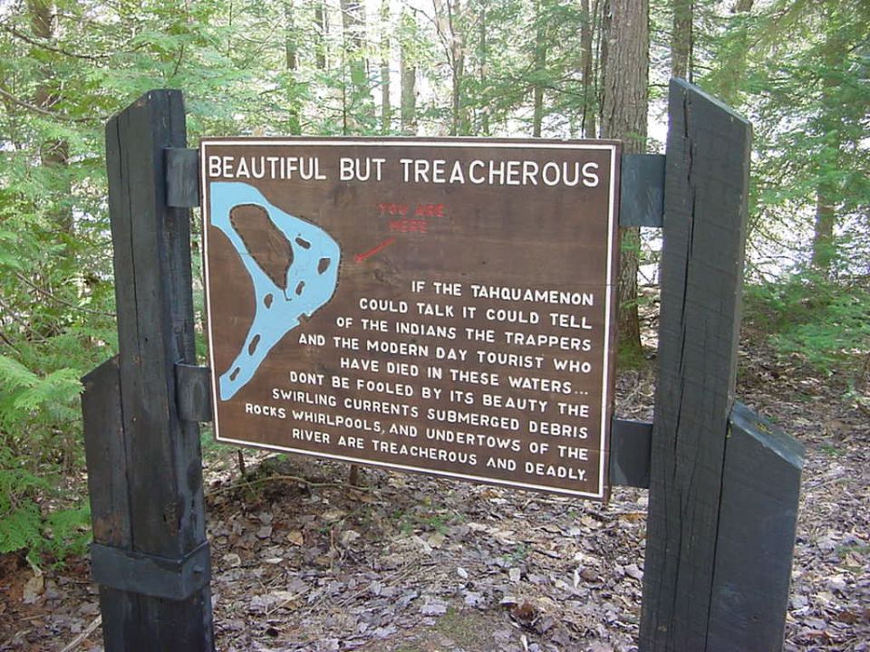 Wooden sign with text about a treacherous river, mounted on posts