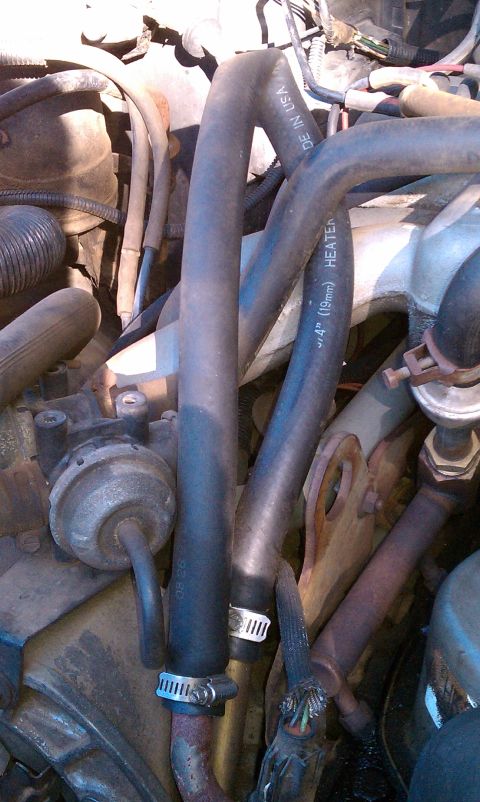 1987 Ford Bronco - Close-up of engine bay components, including heater hoses and vacuum lines.