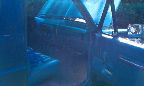 1987 Ford Bronco - The interior of a blue truck is visible with the hood open, revealing the dashboard and seats.