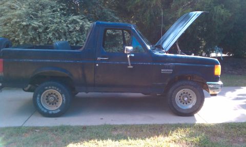 1987 Ford Bronco - A black 1987 Ford Bronco is shown from the side with its hood up.