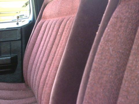 1976 Chevrolet C/K Pickup - Close-up of the interior of a vehicle, showing the textured fabric of the bench seat.
