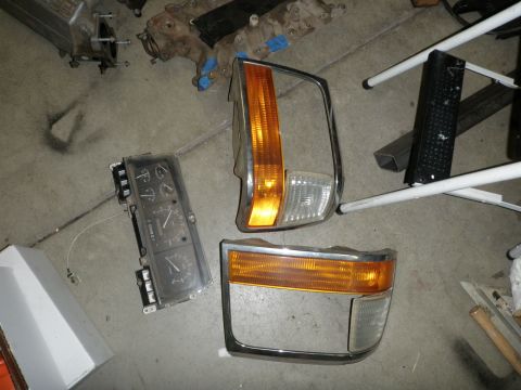 1994 Ford Bronco - Instrument cluster and headlight parts are laid out on a concrete floor.