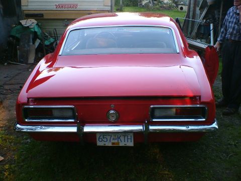 1989 Ford Bronco - Rear view of a red coupe with chrome bumper and rectangular taillights.