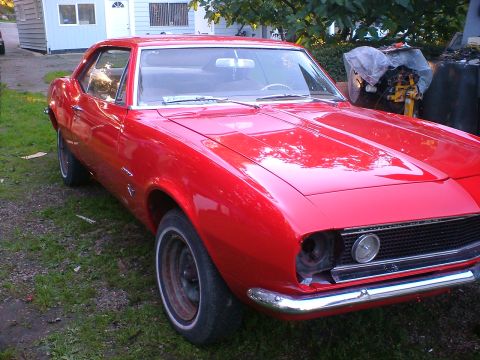 1989 Ford Bronco - This red 1967 Chevrolet Camaro is missing its headlights and parked outside.