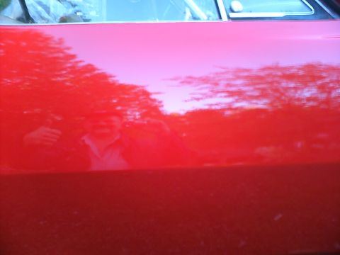 1989 Ford Bronco - Reflection of a man giving a thumbs up on a shiny red vehicle door. The Supermotors.net logo is visible in the lower right corner.