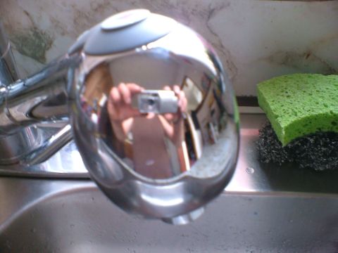 1989 Ford Bronco - A reflection in a faucet shows a person holding a camera, with a sponge nearby.